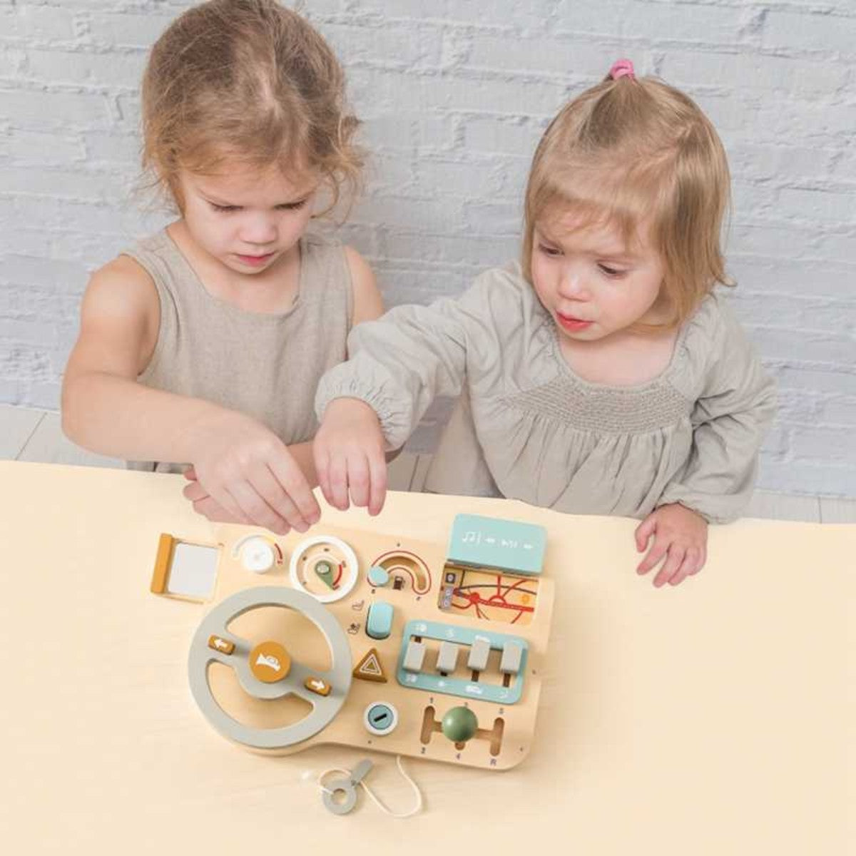 Two girls sitting at a table playing with Montessori wooden busy car board for cooperative learning
