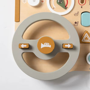 Close-up of wooden steering wheel with horn and turn signal buttons on Montessori busy car board