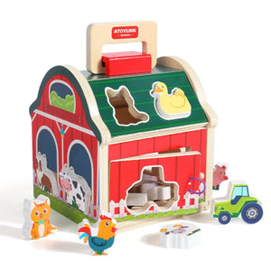 A wooden Montessori toy house with farm animal shapes and color sorting blocks. The toy house is red with cartoonish farm animals and a green roof.